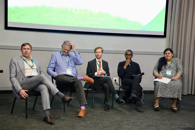 A panel of five speakers seated on stage during a discussion