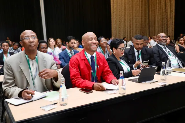 Delegates seated at a table, smiling during a conference session