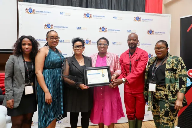 A group of officials posing with a framed certificate at a Gauteng Province event